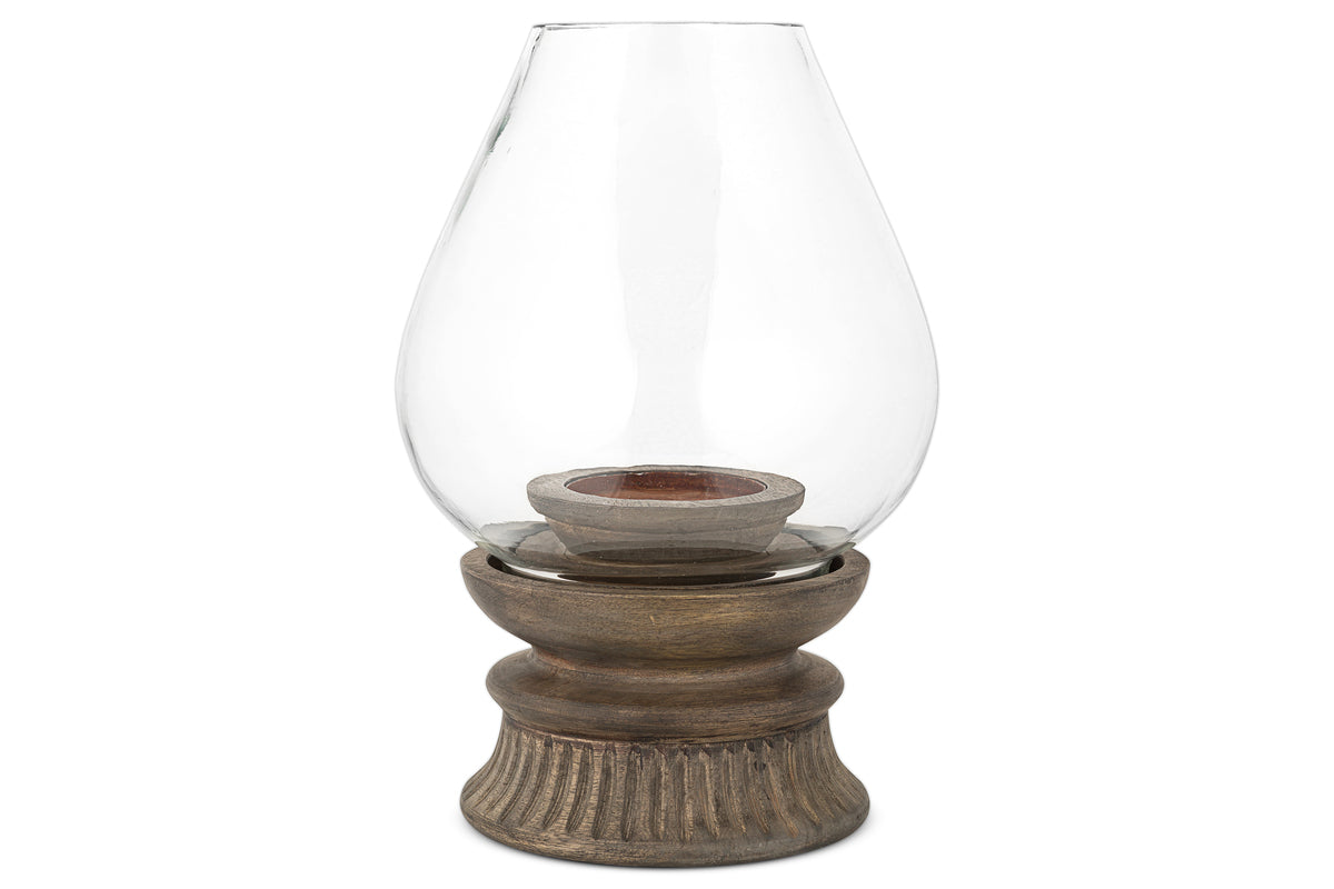 The nkuku Kawani Mango Wood Lantern in Dark Ash features a glass vase on a mango wood stand, ideal for displaying rustic pillar candles.