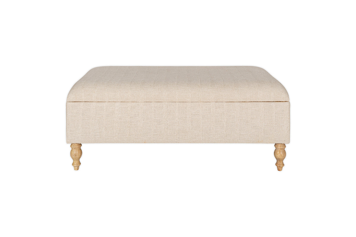 The Kiana Upholstered Storage Ottoman in Natural by nkuku, shown front-facing against a white background, features wooden legs and offers versatile storage and cushioned seating for your living space.