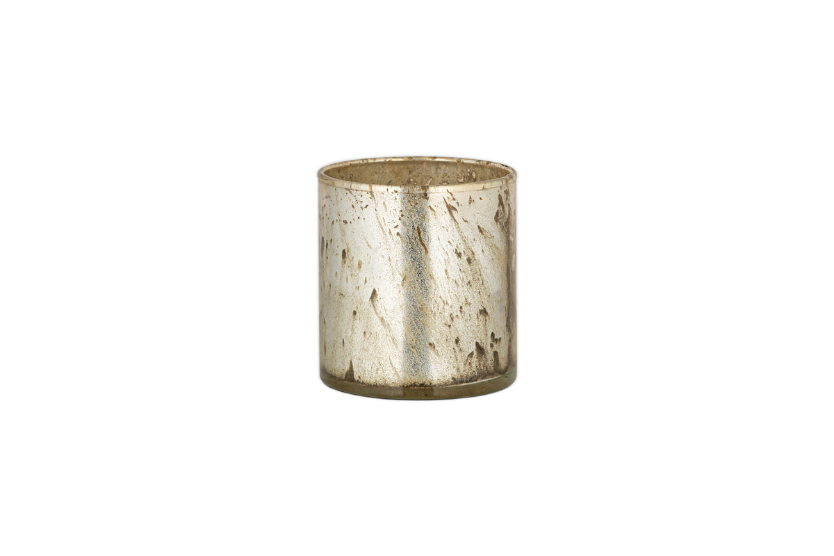 The Kunjari Tealight Holder by nkuku features a small, cylindrical metallic design with a rustic gold-speckled finish, perfect for tealights and adding vintage charm. Shown here against a plain white background.
