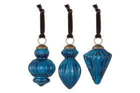 The nkuku Manipur Baubles - Indigo (Set of 3) feature uniquely shaped blue glass ornaments with ribbed textures, vintage silver tops, and brown velvet ribbons—elegant, antique-finished festive decor inspired by classic Christmas styles.
