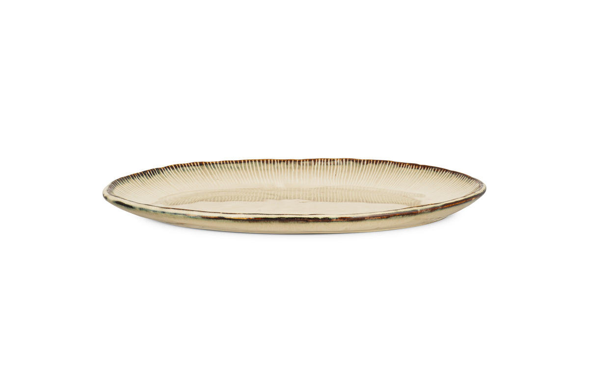 The nkuku Malia Large Oval Platter in cream features an organic shape, beige and brown reactive glaze, and a subtle ribbed rim texture, shown on a plain white background.