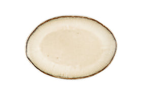 The nkuku Malia Large Oval Platter - Cream features an organic oval shape, cream center, subtle textured lines radiating outward, and a slightly darker irregular rim. The empty ceramic platter is set against a white background.