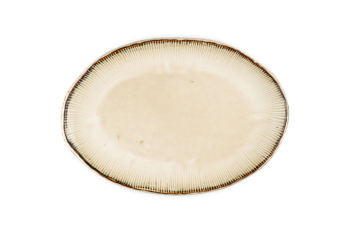 The nkuku Malia Large Oval Platter - Cream features an organic oval shape, cream center, subtle textured lines radiating outward, and a slightly darker irregular rim. The empty ceramic platter is set against a white background.