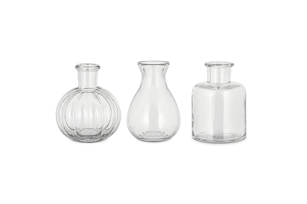 The nkuku Mayumi Recycled Glass Bud Vases - Clear (Set of 3) features three uniquely shaped clear vases, perfect for showcasing your favorite stems as elegant bud vases.
