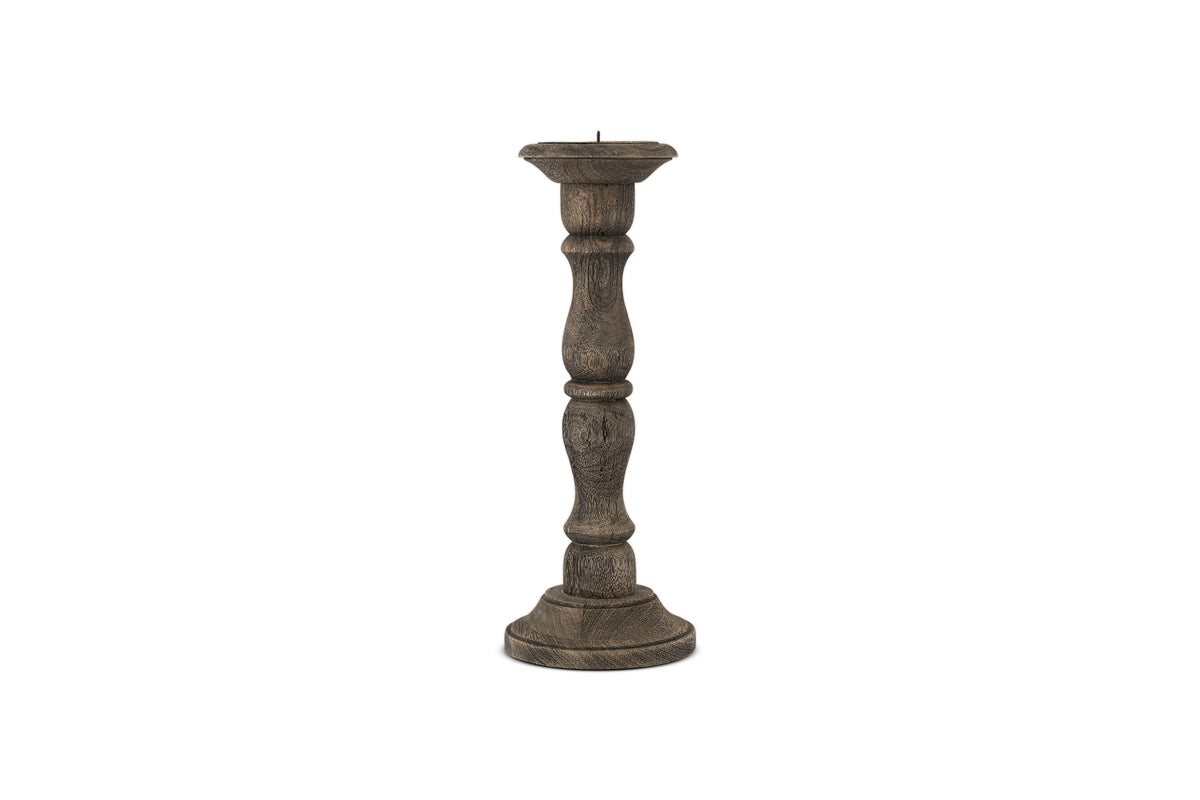 The Nayati Rustic Wood Pillar Candle Stick by nkuku features a tall, dark-stained sustainable mango wood design with a rounded base and ornate column. It has a flat top with metal spike, perfect for rustic decor. Shown on a plain white background.
