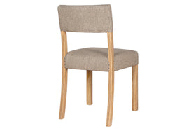 The Nadeeka Linen Upholstered Dining Chair by nkuku features a mango wood frame and legs, with a cushioned seat and backrest in soft grey textured fabric, shown angled slightly to the left.