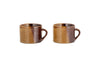 The nkuku Naav Mugs - Mustard (Large, Set of 2) are displayed side by side on a white background, each featuring a handle and unique glaze with subtle color variations.