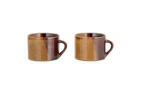 The nkuku Naav Mugs - Mustard (Large, Set of 2) are displayed side by side on a white background, each featuring a handle and unique glaze with subtle color variations.