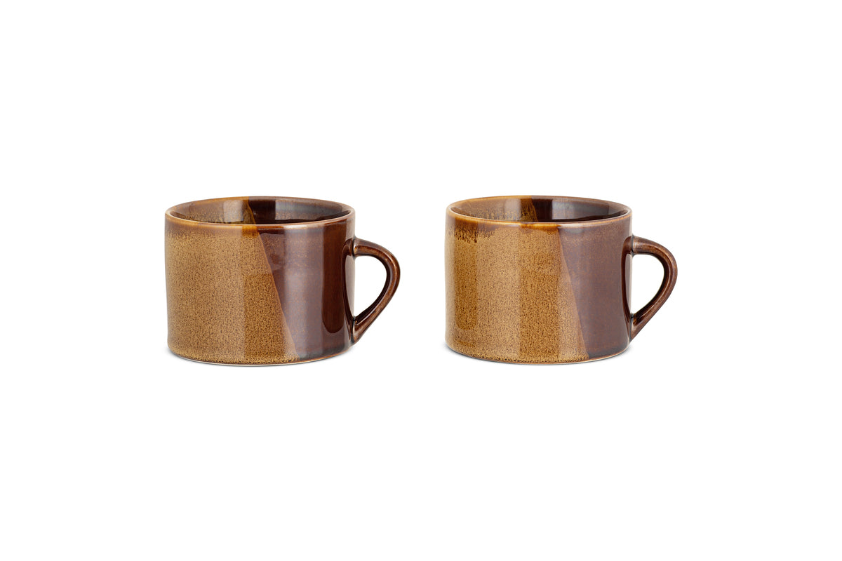 The nkuku Naav Mugs - Mustard (Large, Set of 2) are displayed side by side on a white background, each featuring a handle and unique glaze with subtle color variations.