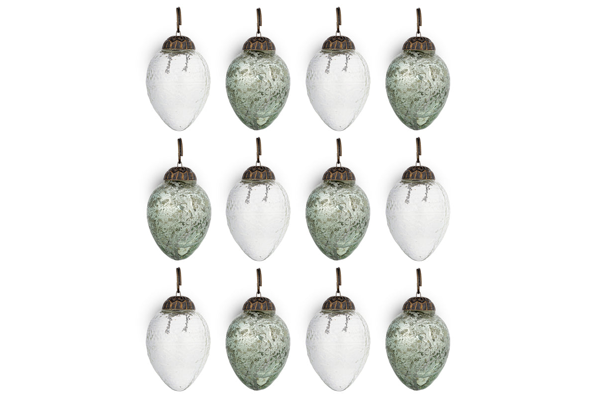 The nkuku Enia Mini Hanging Egg Decoration set includes 12 vintage-style ornaments in antique teal and clear, each with an antique brass cap and brown loop, arranged in a 3x4 grid against a white background.