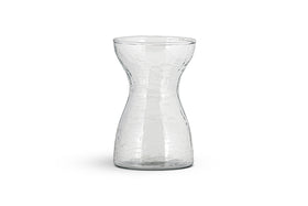 The Enir Hyacinth Vase - Clear by nkuku features clear hammered glass with a textured, dimpled surface and a narrow neck that curves to wide openings. The empty vase is shown against a plain white background.