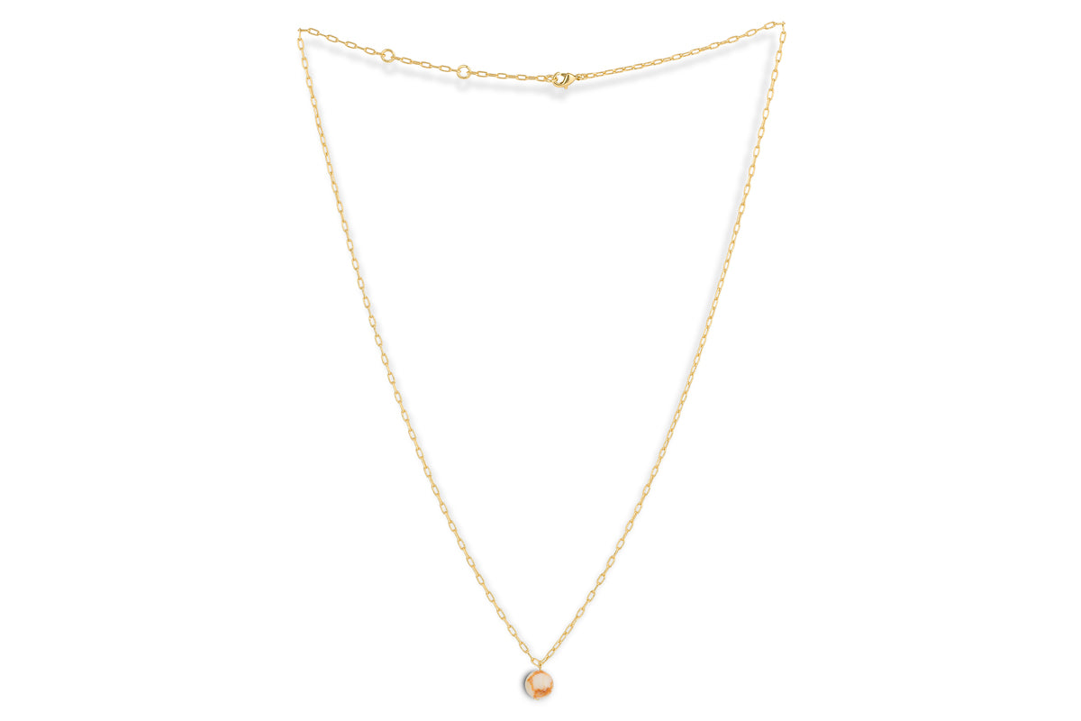 The Cerita Rhodochrosite Necklace by nkuku features a delicate gold chain and a round pink-and-white marbled rhodochrosite pendant in a simple bezel, elegantly displayed on a plain white background.