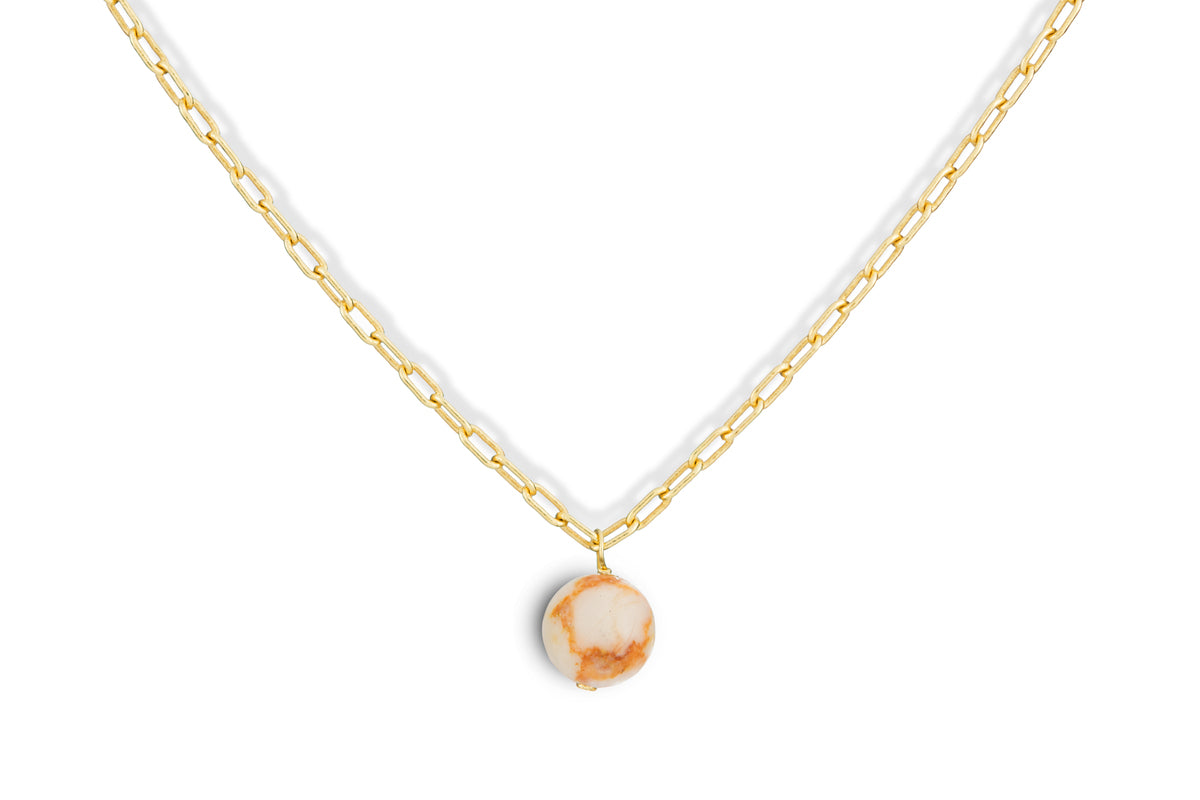 The Cerita Rhodochrosite Necklace by nkuku features a gold chain with elongated links and a striking rhodochrosite and gold-plated pendant, blending beige and light brown tones—an elegant jewellery gift.