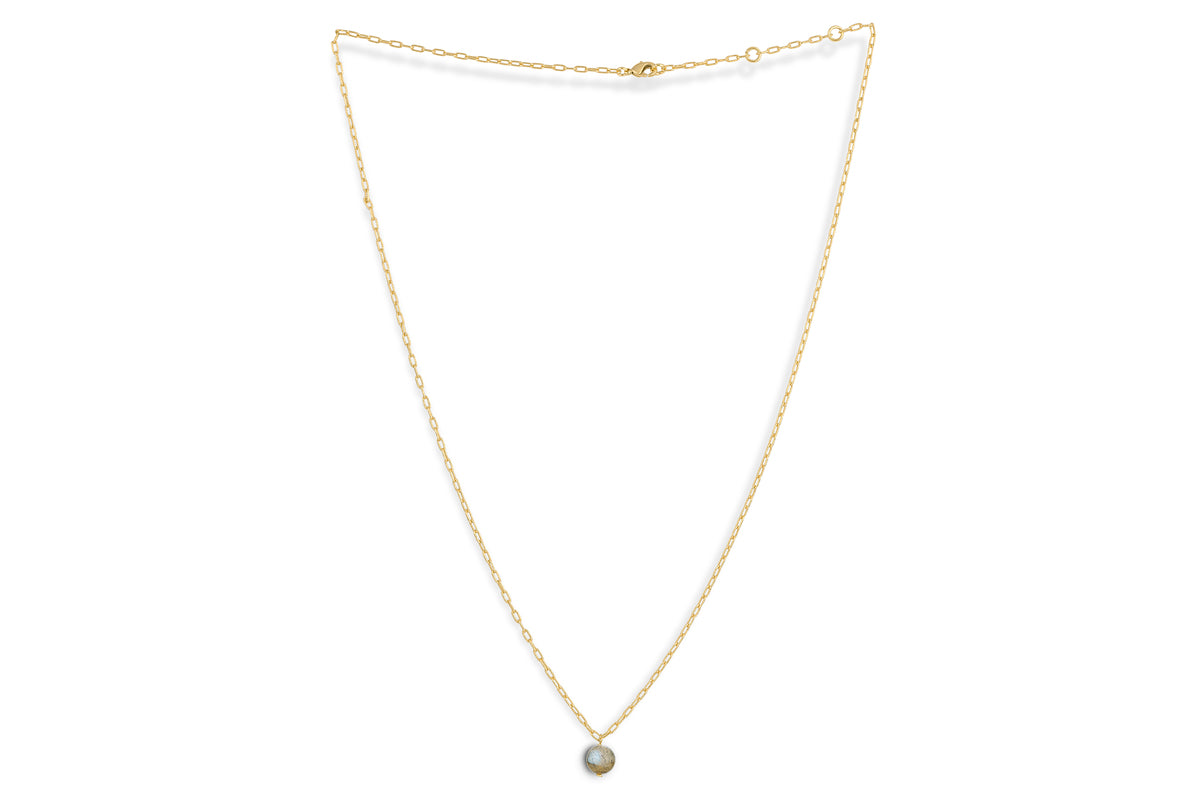 The Marai Labradorite Necklace by nkuku features a delicate gold chain with a round grayish-blue labradorite pendant. The fine, adjustable chain makes it a perfect jewelry gift, shown on a white background.