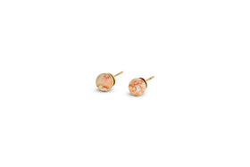The nkuku Cerita Rhodochrosite Stud Earrings feature round marbled peach and cream rhodochrosite stones in a minimal gold-plated bezel, displayed on a plain white background with ample empty space.