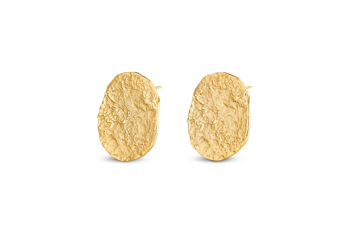 The Oya Hammered Earrings - Gold from nkuku feature an oval shape, textured matte finish, and organic outline, making them striking statement jewellery—perfect for elevating any look.