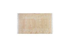 The nkuku Aqil Jute & Cotton Rug - Natural is a rectangular beige rug with white and tan geometric patterns, symmetrical borders, and short white fringe on the shorter edges, shown on a plain white background.