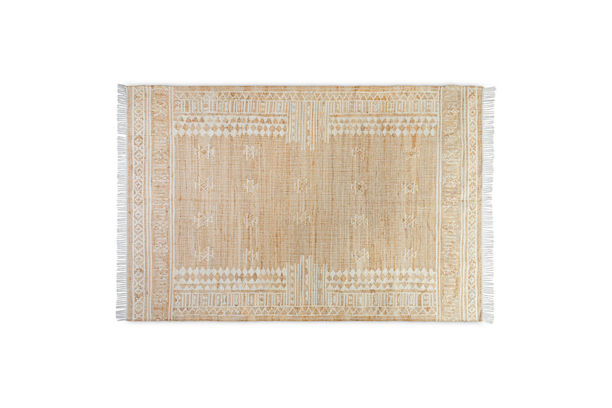The nkuku Aqil Jute & Cotton Rug - Natural is a rectangular beige rug inspired by traditional Indian design, featuring white geometric tribal patterns and fringed edges, displayed on a plain white background.
