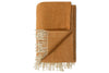 The nkuku Ilaa Wool Throw - Sand is shown folded, featuring rust-orange stripes, thin white stripes, and cream fringe. One corner is turned to display the soft, textured wool on both sides and the full length of the fringe.
