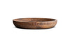 The Eisha Bowl - Brown by nkuku is a shallow wooden serving bowl with a wide, hand-carved rim, smooth interior, and vertical carved grooves on the exterior. Its natural brown finish highlights the wood’s unique grain against a white background.