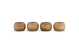 The nkuku Vivan Napkin Rings - Natural - Set of 4 features small, rounded wooden rings with a natural finish and unique wood grain, bringing handcrafted charm to your table decor.