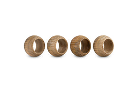 The nkuku Vivan Napkin Rings - Natural - Set of 4 features handmade brown wooden rings with grooved, textured surfaces and unique wood grain—perfect for elevating your table decor.