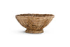 The Bersama Rattan Fruit Bowl - Natural by nkuku is a round, shallow handwoven rattan bowl with slightly flared sides and a sturdy base, making it an ideal kitchen centrepiece that highlights its beautiful textured weave.