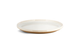 The Edo Dinnerware Set - Terracotta by nkuku features 12 minimalist, round ceramic plates with glossy white interiors and matte tan rims and bases. The design's earthy tones and lack of decoration create a serene, stylish tabletop look.