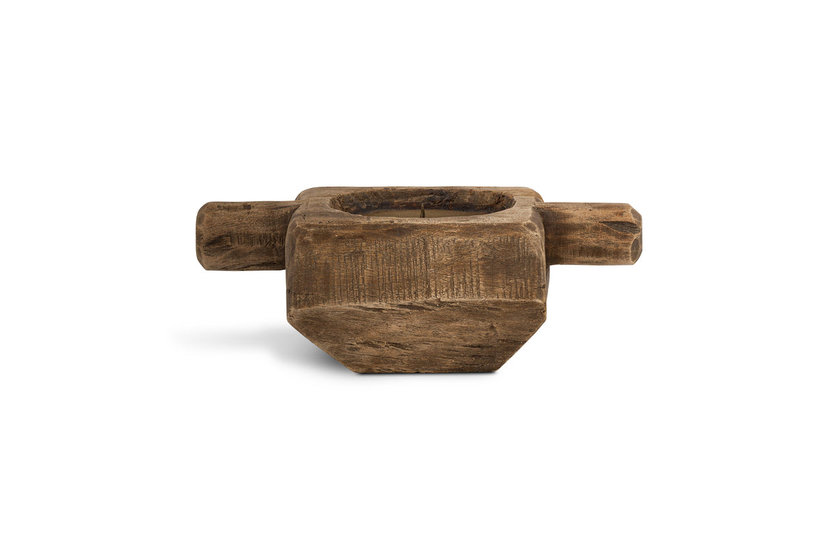 The nkuku Apu Reclaimed Wood Traditional Candle Holder - Natural features a rustic, square design with a deep center and two cylindrical handles, showcasing weathered surfaces and natural grain for an aged, handcrafted look.