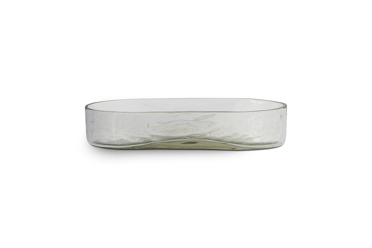 The Ilcoso Recycled Hammered Glass Soap Dish by nkuku features clear, rectangular glass with rounded corners, a low wide profile, and a subtle wavy texture. Shown empty against a plain white background.
