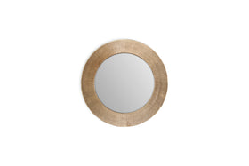 The Putali Etched Mirror by nkuku features a wide, textured antique brass frame with fine radiating lines. Its round design and decorative details make it a striking centerpiece on any plain white wall.