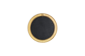The Putali Etched Mirror - Antique Brass by nkuku is a sculptural wall mirror with a wide gold-toned rim adorned with subtle engravings, a rectangular top detail, and a solid black center, shown from above on a white background.