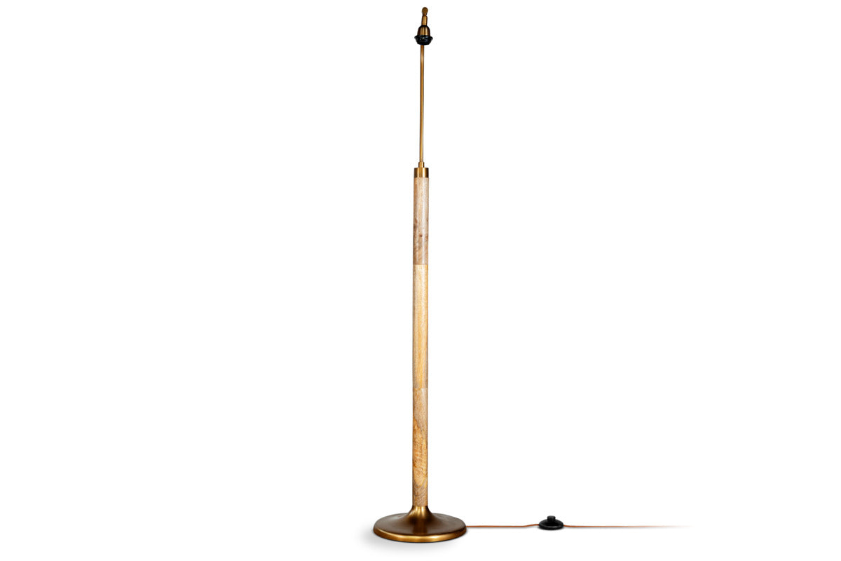 The nkuku Kera Wood & Metal Floor Lamp features an antique brass round base and stem, a natural mango wood midsection, no shade, a visible bulb socket on top, and a foot switch on the cord.