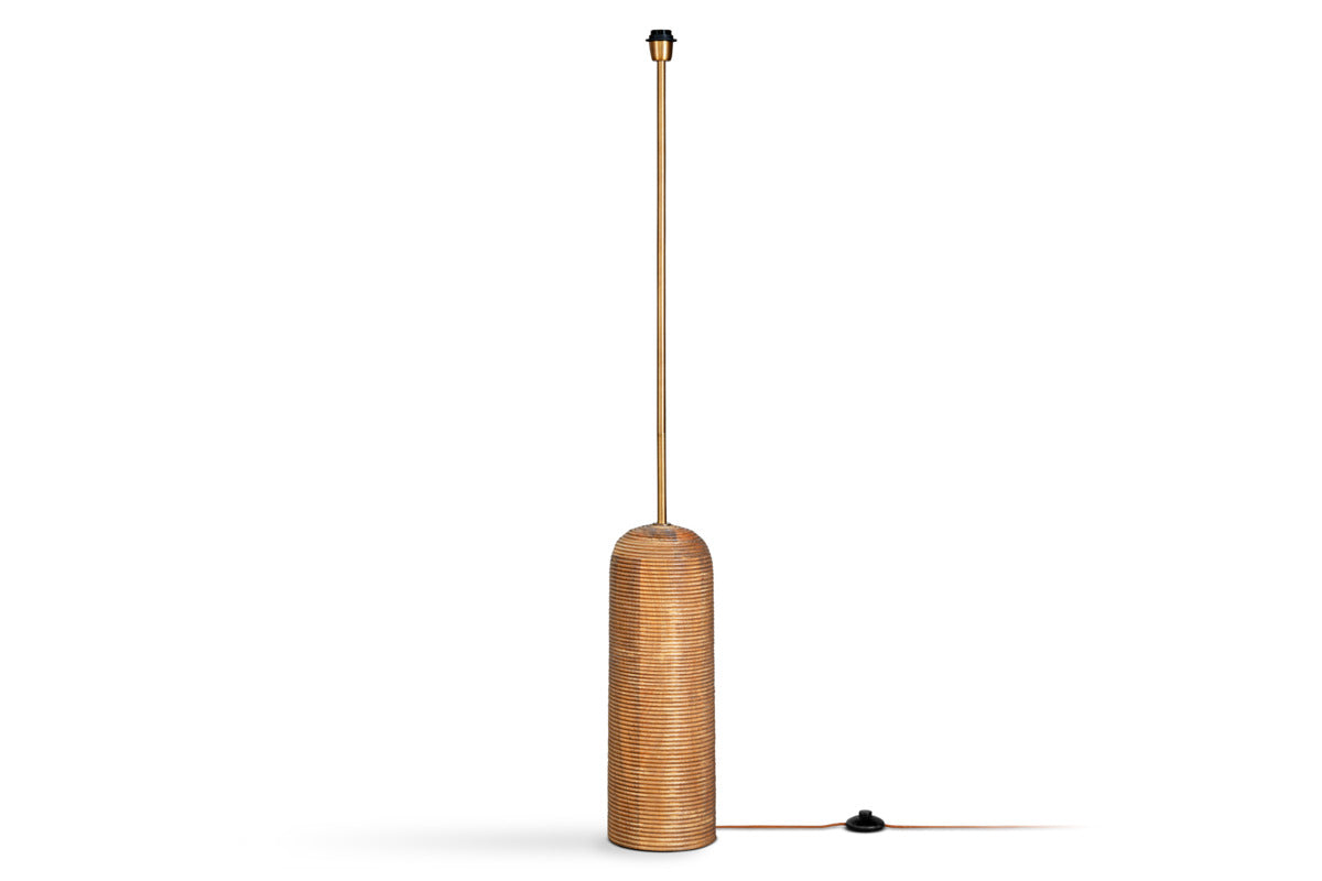 The nkuku Agua Grooved Floor Lamp - Natural features a tall, cylindrical design with a ribbed mango wood base in warm brown, slender pole, black light socket, and a handy foot switch—ideal for modern spaces.