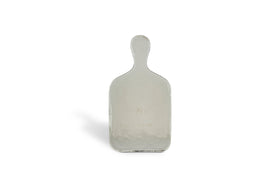 The Komal Serving Platter - Clear by nkuku is a small, rectangular glass platter with a rounded handle, standing upright on a plain white background and casting a faint shadow to the left.