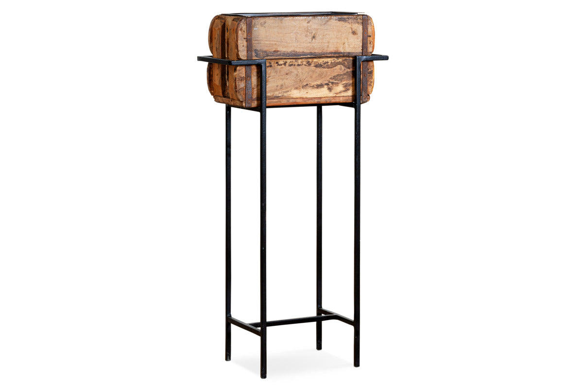 The nkuku Amazzi Indoor Planter Stand – Natural & Black features a rustic rectangular reclaimed wooden planter atop a tall black metal frame, blending vintage charm with modern style for an elegant indoor plant display.