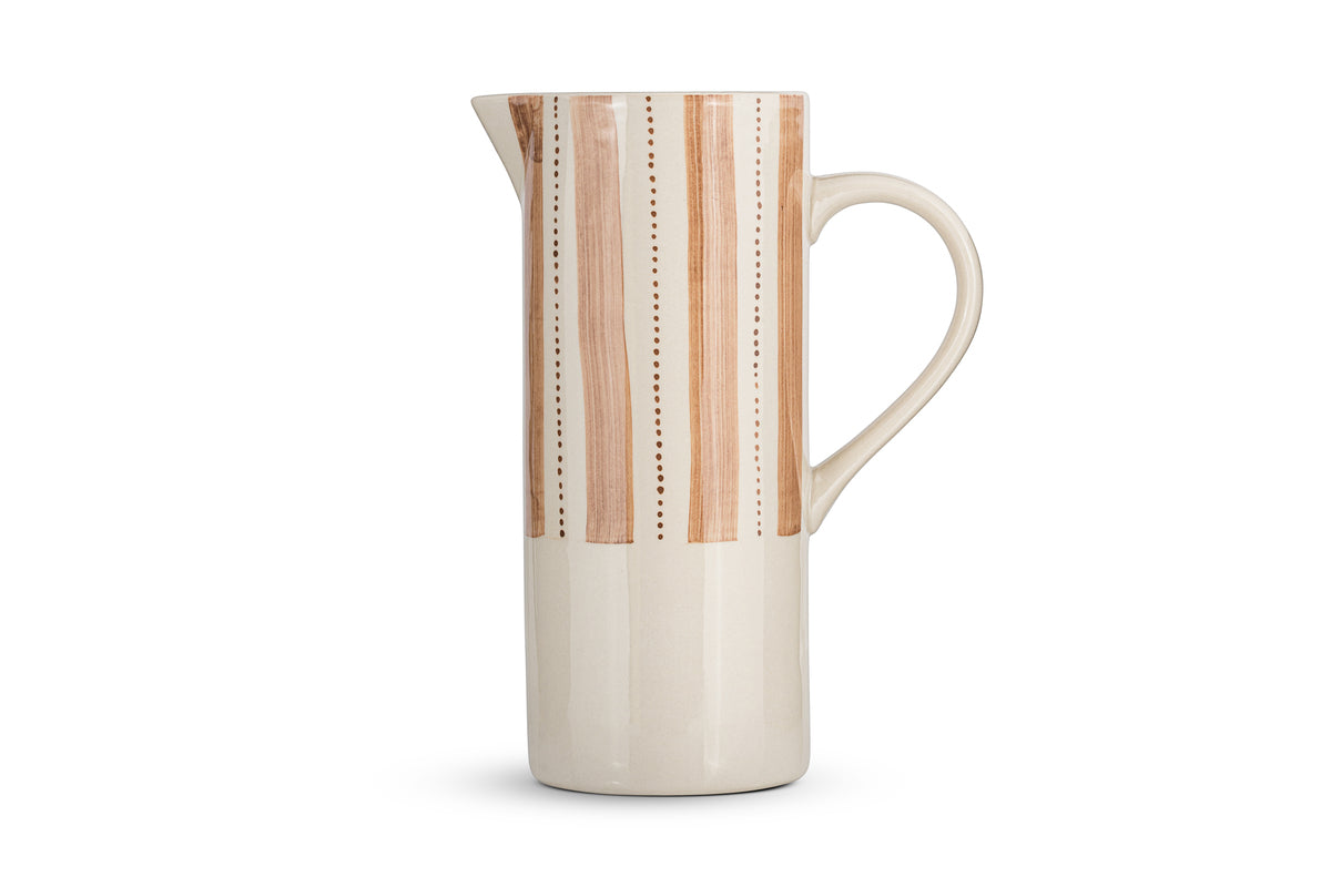 The nkuku Patthar Jug - Cream & Clay - Large is a hand-painted ceramic jug with a tall, cylindrical shape, narrow spout, and curved handle. Its upper half displays tan and brown stripes with dotted lines on cream; the lower half is solid cream.