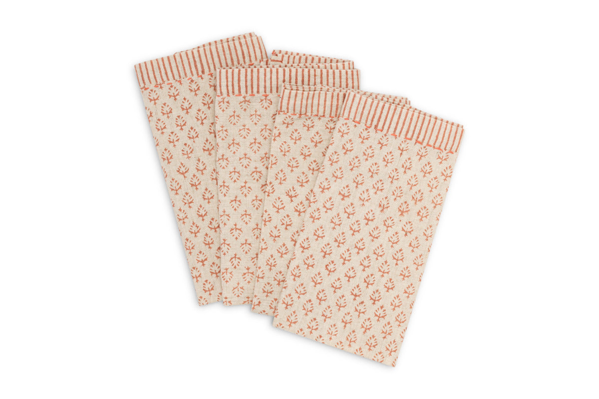 The nkuku Peplu Block Print Napkin - Terracotta, set of 4, features a charming red floral pattern with red and beige striped borders—perfect rustic table accessories or Indian-inspired napkins, elegantly displayed on a white background.
