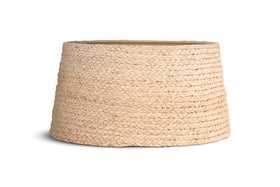 The Pisang Natural Lampshade by nkuku features a woven, light beige seagrass design with a wide, round base that tapers at the top. Its organic texture resembles a basket and is shown on a white background with a faint shadow to the left.