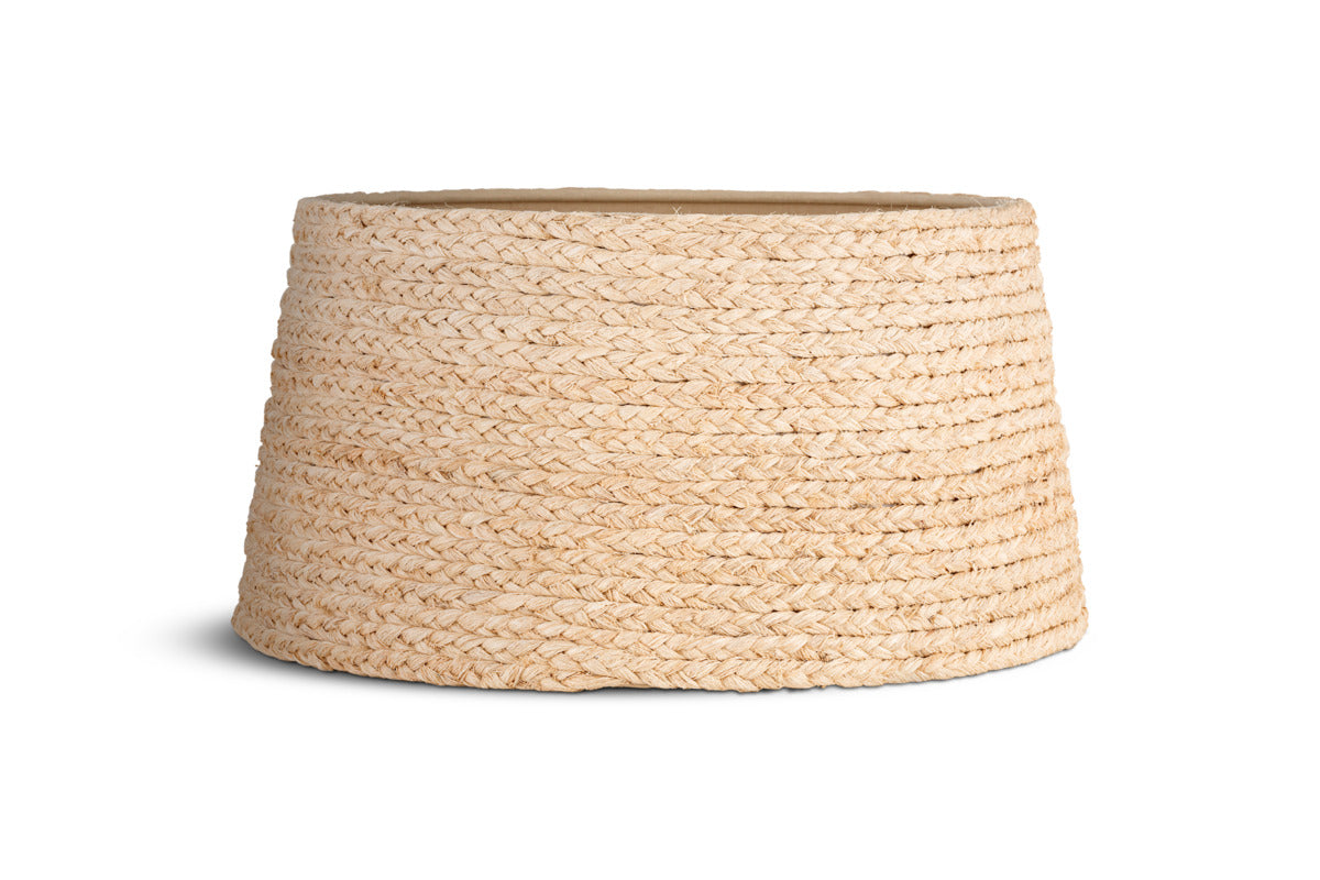 The Pisang Natural Lampshade by nkuku features a woven, light beige seagrass design with a wide, round base that tapers at the top. Its organic texture resembles a basket and is shown on a white background with a faint shadow to the left.
