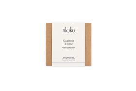 A rectangular nkuku Oakmoss & Rose 3 Wick Scented Candle - Yellow box with brown sides and a white label. This 170g candle features a spring scent, natural wax, unique essential oils, and comes in a recycled glass vessel.