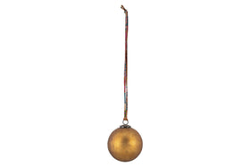 The nkuku Oko Giant Bauble - Matt Gold features a slightly mottled finish and hangs from a vibrant, patterned ribbon, making it a charming addition to festive décor against any plain background.
