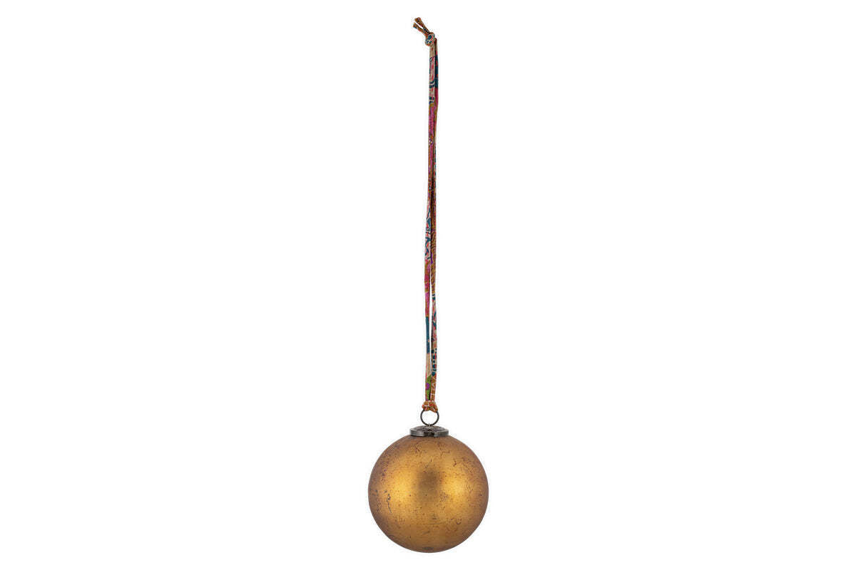 The nkuku Oko Giant Bauble - Matt Gold features a slightly mottled finish and hangs from a vibrant, patterned ribbon, making it a charming addition to festive décor against any plain background.