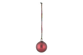 The nkuku Oko Giant Bauble - Matt Bordeaux features a slightly weathered red finish and a small metal cap, hanging from a multicolored string. Its elegant design makes it a charming addition to any festive display.