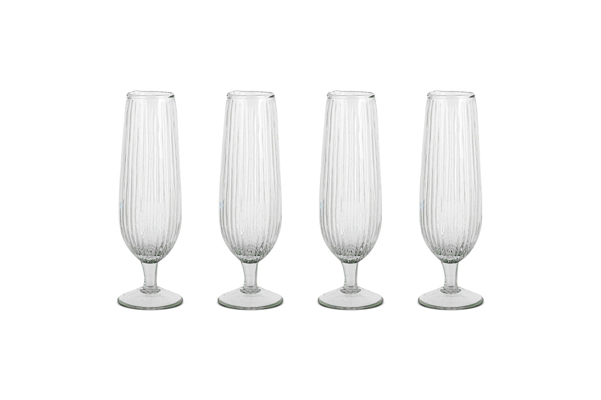 The Otuba Champagne Flute - Clear (Set of 4) by nkuku features four ribbed, recycled glass flutes arranged in a row on a white background.