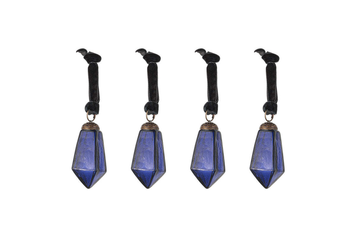 The nkuku Ratnam Baubles - Indigo - Small (Set of 4) feature faceted deep blue crystal points with an antique glass finish on black velvet ribbons. Each ribbon is topped with a black crow figurine for a gothic, elegant look.