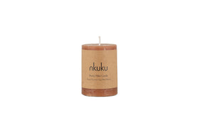 A Rustic Soy Blend Mini Pillar Candle in rust by nkuku with a textured finish and label, shown against a plain white background.