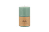 A small sage green Rustic Soy Blend Pillar Candle by nkuku, featuring a textured finish and a brown label, is shown against a white background.