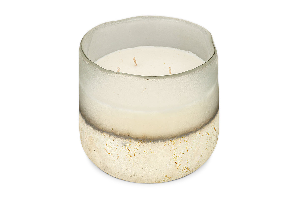 The nkuku Sea Salt & Moss 3 Wick Scented Candle comes in a round, semi-transparent glass holder with a frosted white-to-speckled gold and beige gradient and features a UK-inspired fragrance.