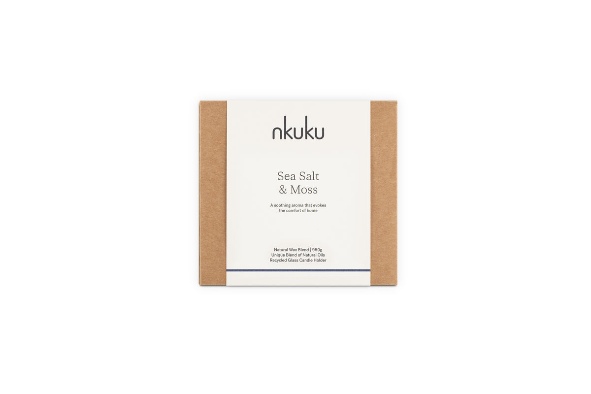 A nkuku Sea Salt & Moss 3 Wick Scented Candle in eco-friendly brown and white packaging features a bespoke, soothing fragrance and a recyclable clear holder. Expertly crafted in the UK.